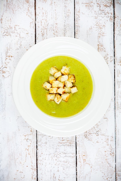 Sopa de crema casera con brócoli y picatostes sobre fondo de madera