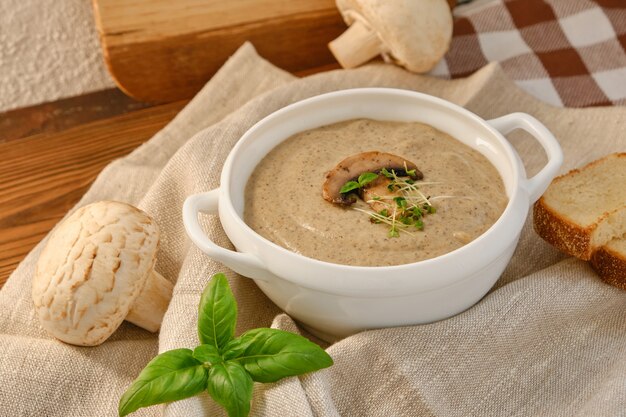 Sopa de crema casera con champiñones champiñones en un tazón blanco, sobre fondo rústico, estilo vintage