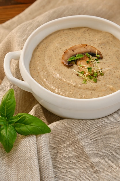 Sopa de crema casera con champiñones champiñones en un tazón blanco, sobre fondo rústico, estilo vintage