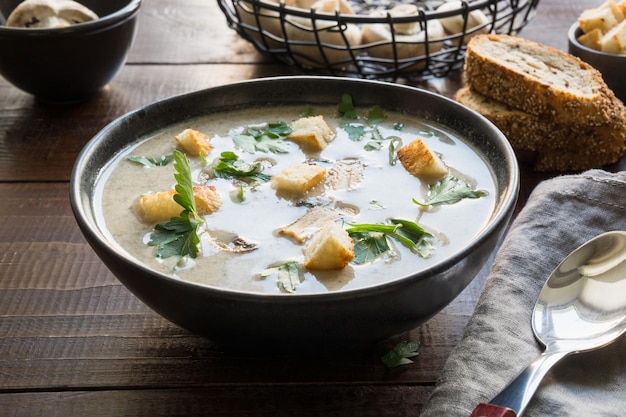 Sopa de crema de champiñones y champiñones en la mesa de madera Cerrar