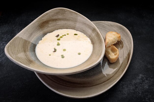 Sopa de crema de champiñones con pan casero sobre hormigón oscuro