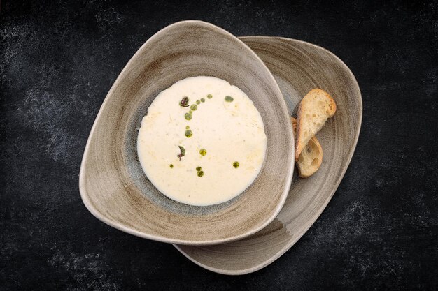 Sopa de crema de champiñones con pan casero sobre hormigón oscuro