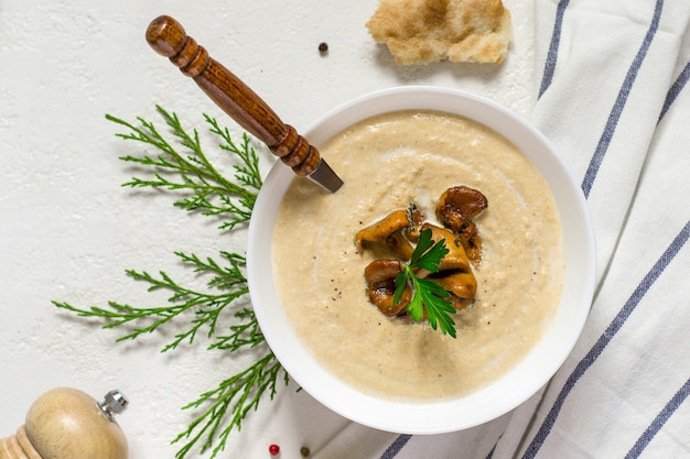 Sopa de crema de champiñones rebozuelos sobre fondo blanco.