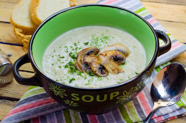 Sopa de crema de champiñones en una sopera sobre una mesa de madera