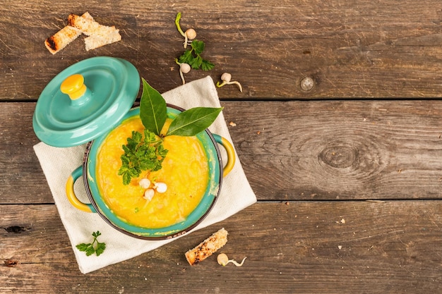 Sopa de crema de guisantes en un tazón sobre fondo de madera vintage Legumbres secas tostadas de crutones y verduras