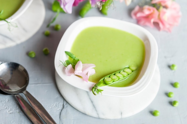 Sopa de crema de guisantes verde fresca casera con brotes de guisantes y flores