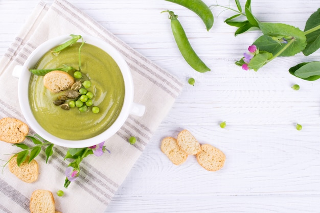 Sopa crema de guisantes verdes con picatostes en un tazón blanco