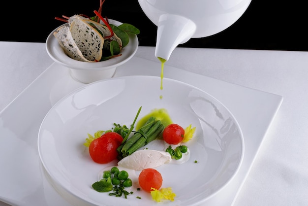 Sopa crema de guisantes verdes con tomates sobre un fondo blanco.