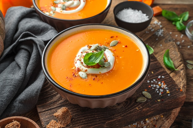 Sopa de crema de otoño con crema y semillas de calabaza sobre un fondo de madera. Vista lateral, primer plano.