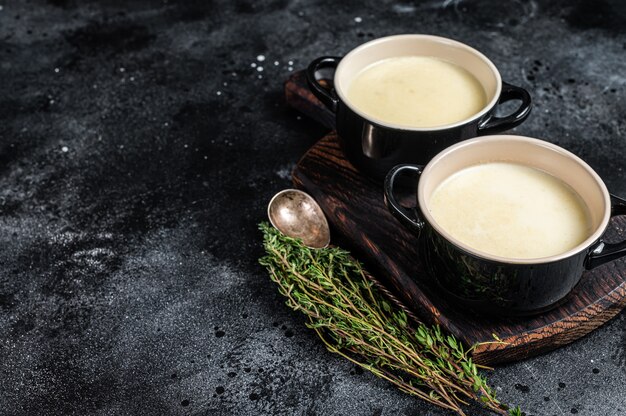 Sopa de crema de patata en tazones sobre la mesa de la cocina. Fondo negro. Vista superior. Copie el espacio.