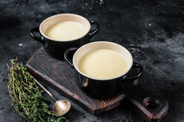 Sopa de crema de patata en tazones sobre la mesa de la cocina. Fondo negro. Vista superior.