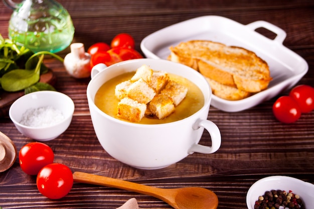 Sopa de crema de queso o cebolla con pan tostado en un tazón blanco