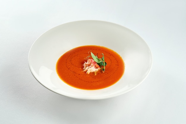 Sopa de crema de tomate al horno con cangrejo en una placa blanca sobre un mantel blanco