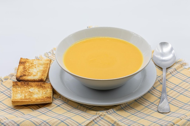 Sopa de crema tradicional hecha de calabaza y zanahorias con pan tostado en un cuenco de cerámica