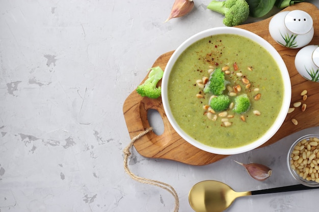 Sopa de crema vegetariana con brócoli, espinacas y calabacín en un tazón blanco sobre fondo gris