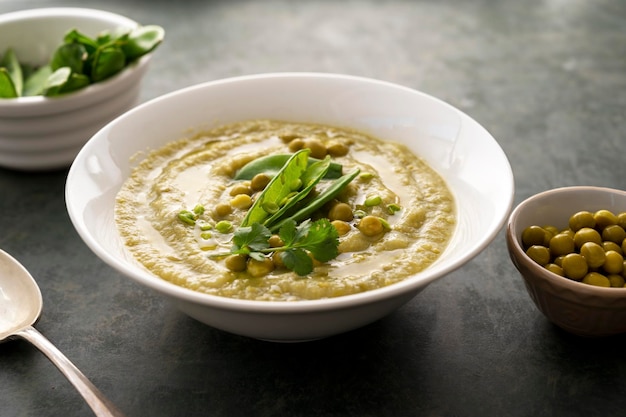 Sopa de crema verde con guisantes verdes frescos en un plato blanco sobre fondo oscuro Comida vegana saludable