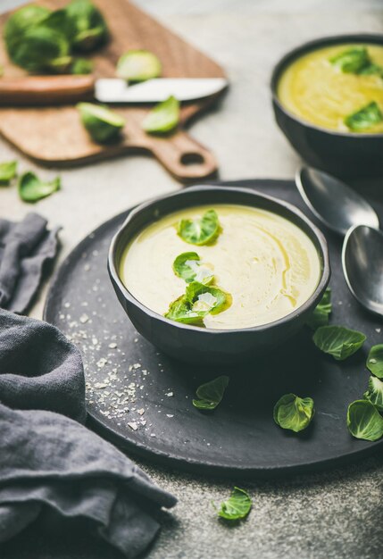 Sopa de crema de verduras con coles de Bruselas en tazones negros enfoque selectivo