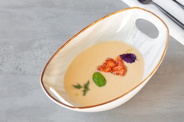 Sopa de crema de verduras en un tazón sobre mesa gris