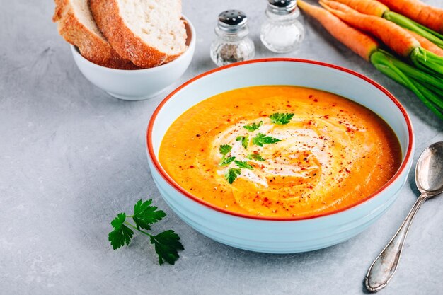 Sopa crema de zanahoria y calabaza con perejil sobre fondo de piedra gris