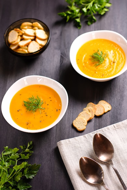 Sopa creme de abóbora com croutons e endro fresco e salsa na mesa de madeira