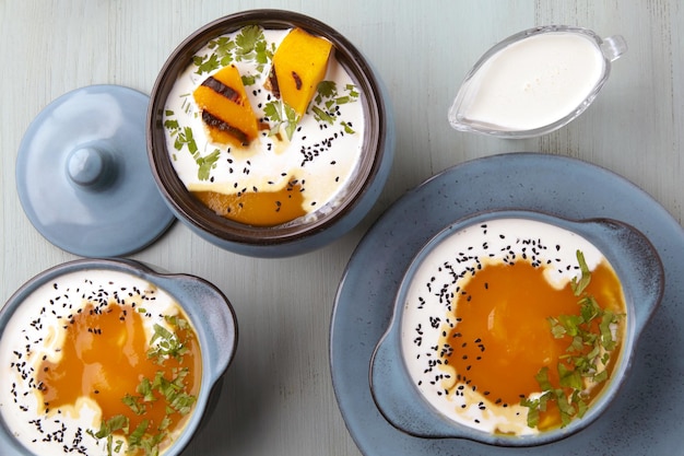 Sopa creme de abóbora com ervas de sementes de cominho preto creme e pão torrado em uma mesa de madeira azul clara