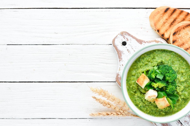 Sopa creme de brócolis, espinafre em uma tigela com pão torrado. Sopa verde. Comida dietética. Vista do topo.