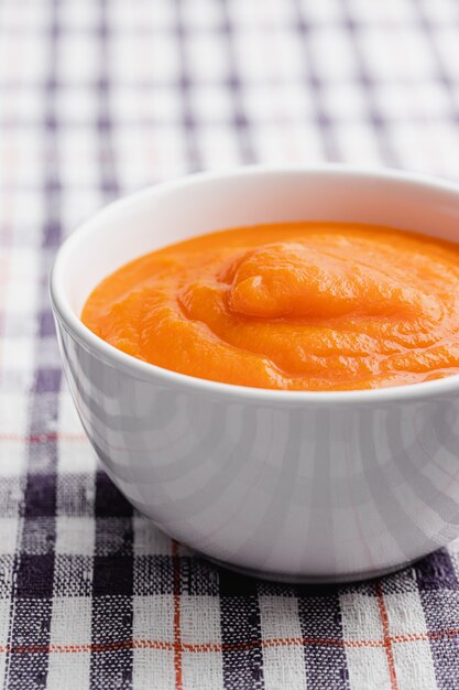 Sopa creme de cenoura em uma tigela branca com guardanapo de pano. copie o espaço.