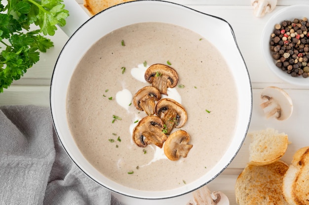 Sopa creme de cogumelos com croutons de creme e ervas em um fundo branco de madeira Comida de conforto