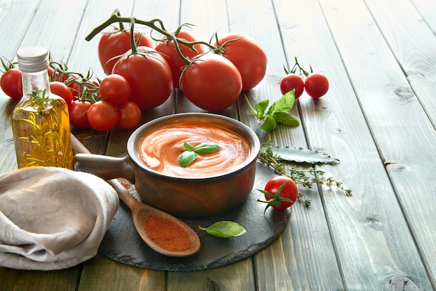 Sopa creme de tomate em uma tigela de cerâmica servida com creme e manjericão, espaço