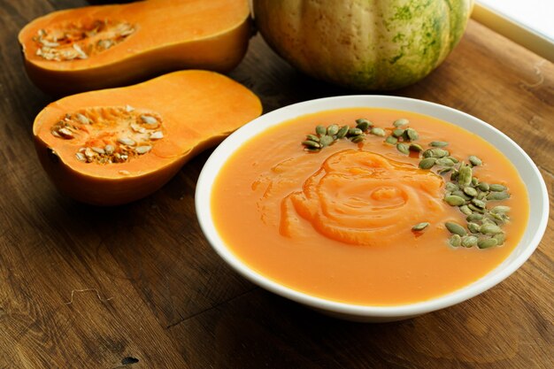 Sopa cremosa de abóbora em uma mesa de madeira marrom