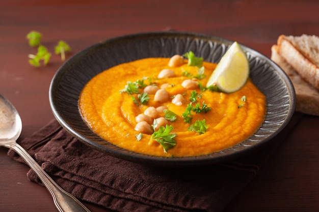 Sopa cremosa de grão de bico de cenoura no fundo rústico escuro