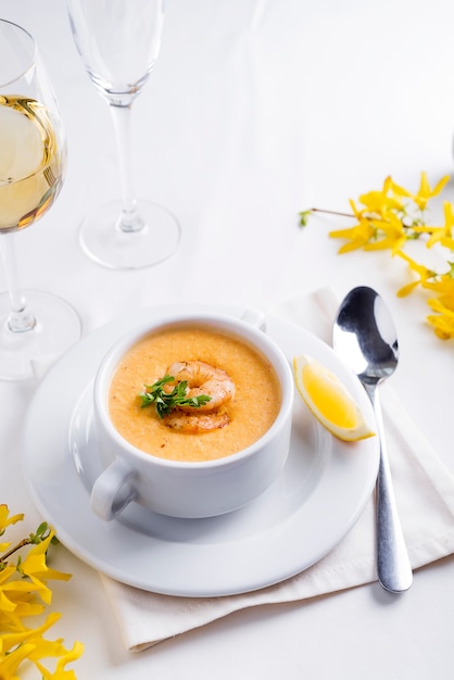 Sopa cremosa do tomate com marisco e limão em um fundo branco.