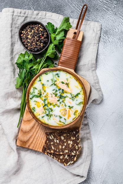 Sopa cremosa finlandesa de pescado con salmón y papas. Fondo gris, vista desde arriba.