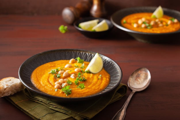 Sopa cremosa de garbanzos y zanahorias sobre fondo rústico oscuro