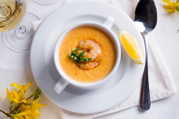 Sopa cremosa con los mariscos y el limón en un fondo blanco.