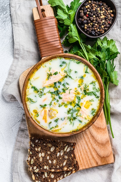 Sopa cremosa de pescado con salmón, trucha, papas y perejil. Superficie gris, vista superior.