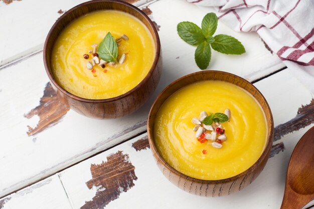 Sopa de abóbora amassada com especiarias em bacias de madeira em placas de luz.