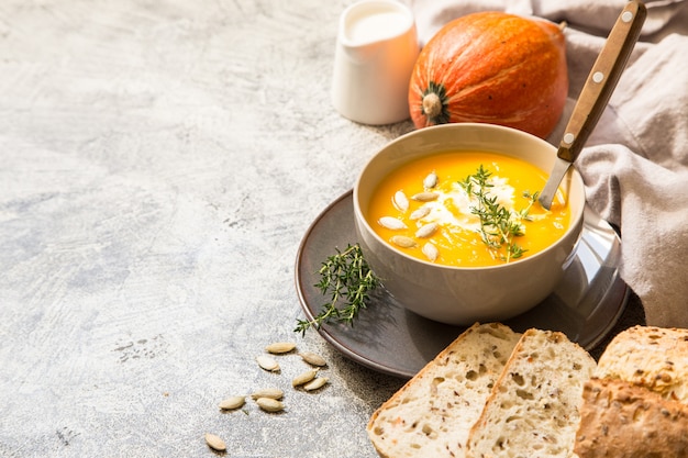 Sopa de abóbora com sementes de abóbora, pão torrado e tomilho com copyspace