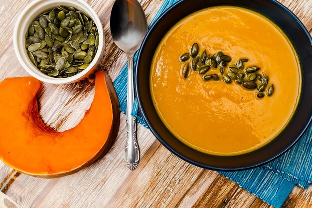 Foto sopa de abóbora de creme adornada com sementes de abóboras em uma mesa de madeira