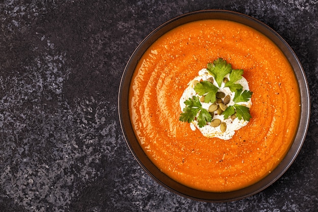 Sopa de abóbora e cenoura com creme, sementes e salsa.