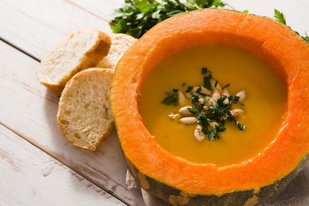 Foto sopa de abóbora e cenoura na mesa de madeira branca. comida de outono.