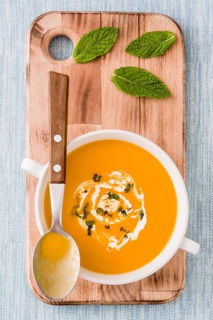 Sopa de abóbora em uma tigela branca na mesa azul