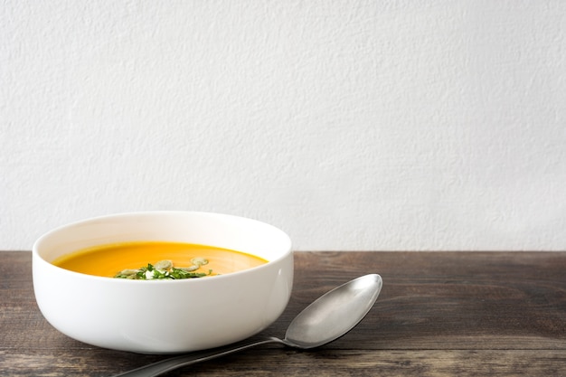 Sopa de abóbora em uma tigela na mesa de madeira. copie o espaço