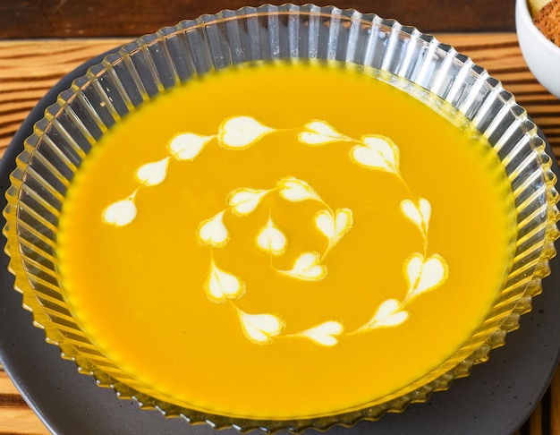 Sopa de abóbora na mesa de madeira com vista lateral para biscoitos