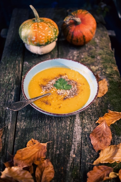 Foto sopa de abóbora no prato de outono de mesa de madeira