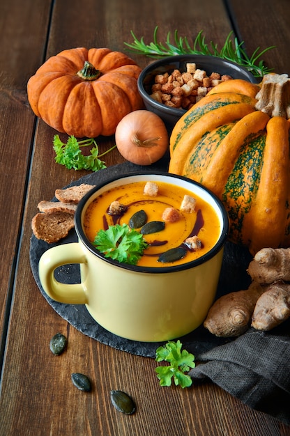 Sopa de abóbora picante com gengibre e cebola, servida em caneca com óleo de abóbora, sementes e croutons