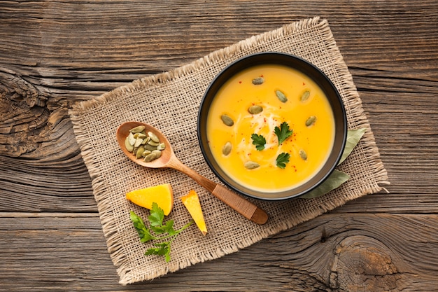 Sopa de abóbora plana leigos em tigela com colher de pau