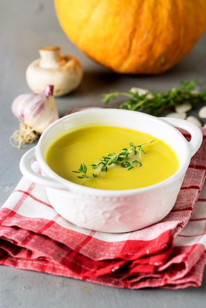 Sopa de abóbora saborosa com creme em fundo cinza ervas de abóbora crua alho vertical