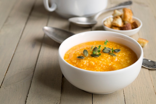 Sopa de abóbora vegetariana em uma mesa de madeira.