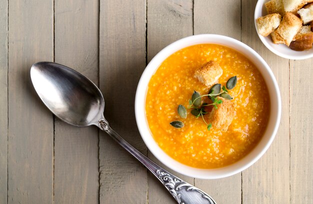 Sopa de abóbora vegetariana em uma mesa de madeira.